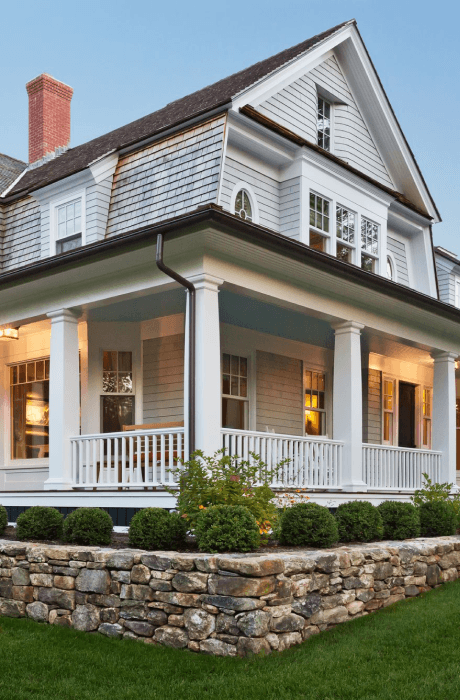 White colonial-style house with a stone wall and front lawn