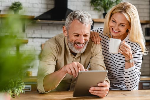 Smiling couple looking at a tablet together in their kitchen