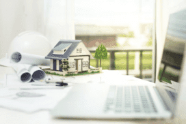 Model house on a desk next to a laptop