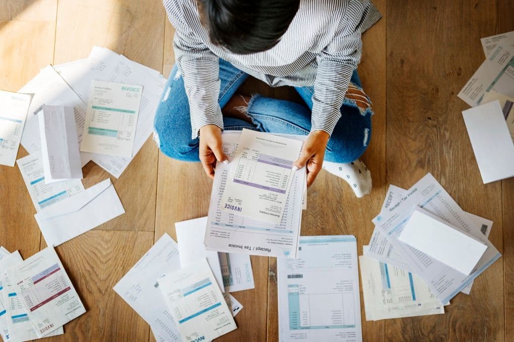 Woman sorting her financial paperwork on a hardwood floor