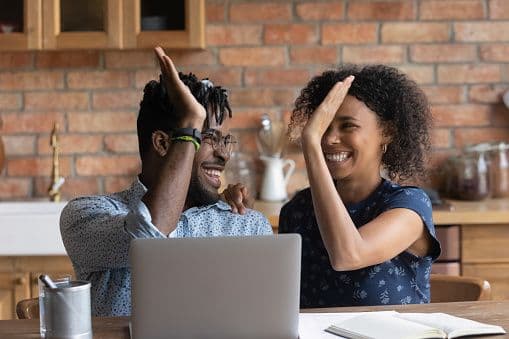 Couple high-fiving at their kitchen table