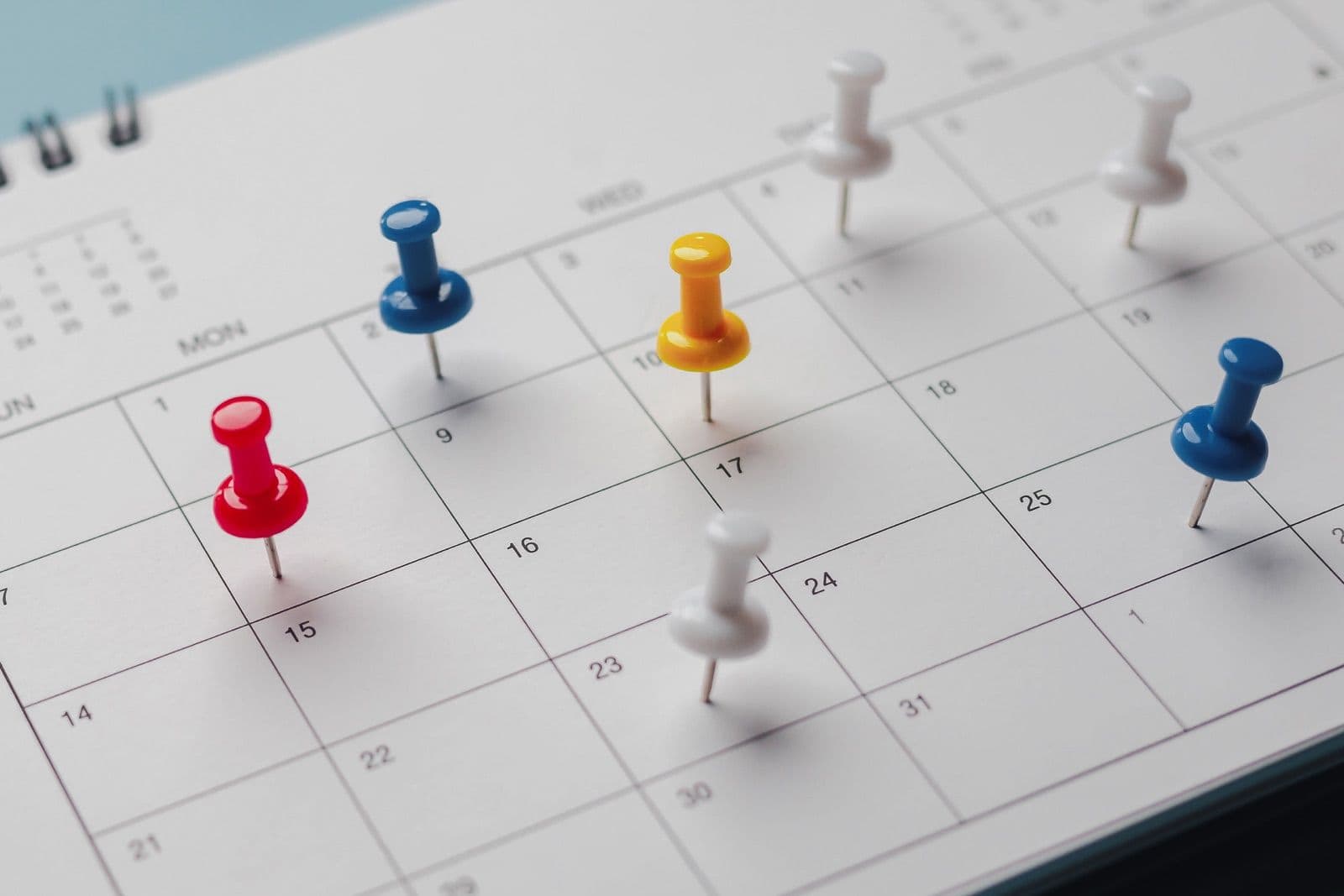 Wall calendar with colored pins marking dates