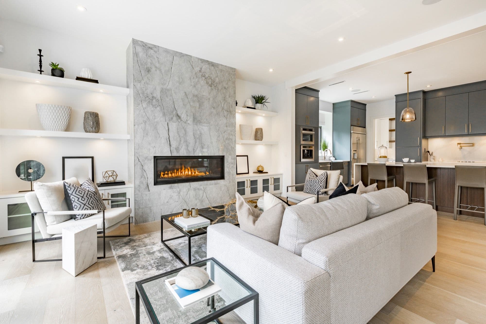 Bright, staged living room with a marble fireplace and an open kitchen
