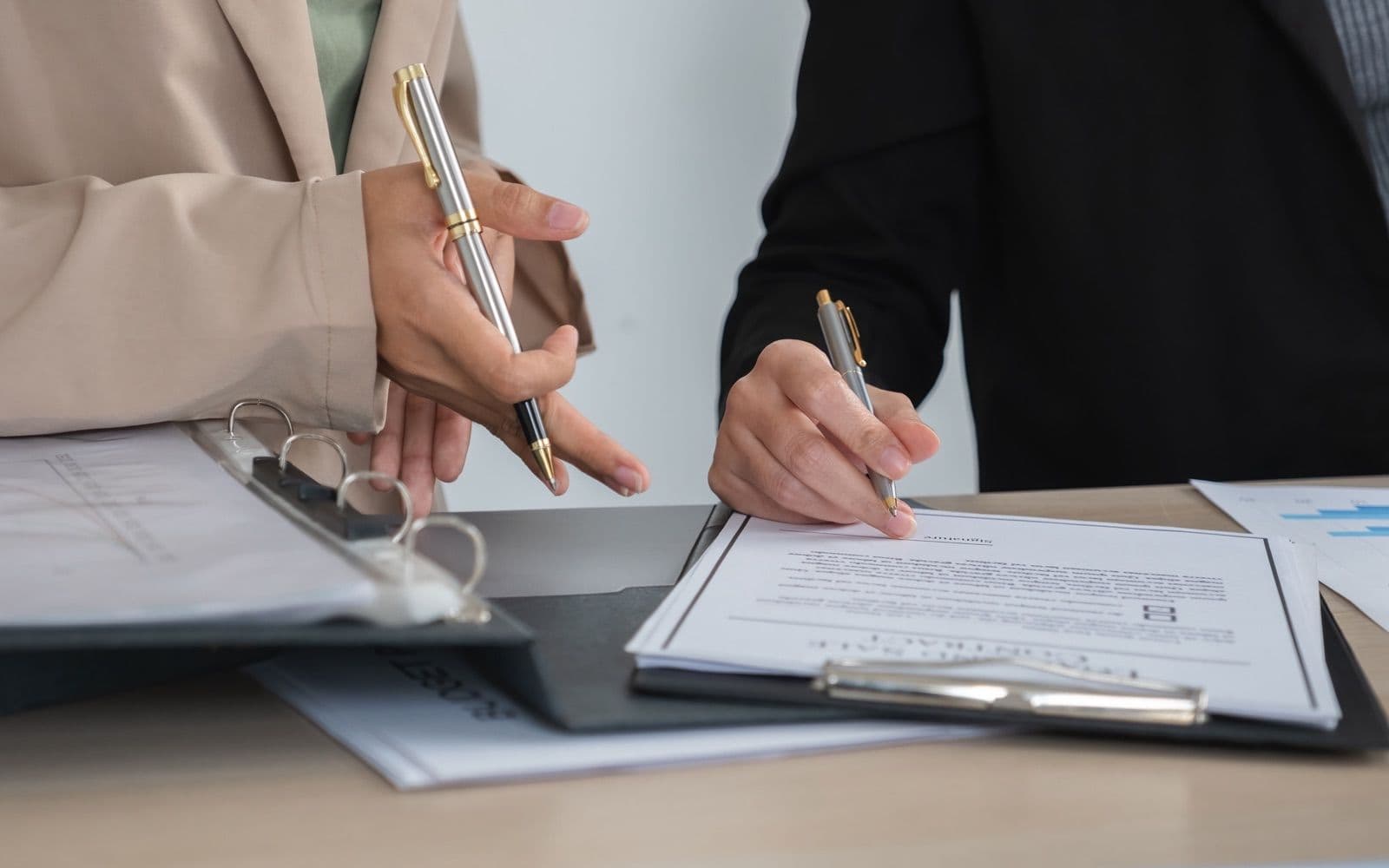 Two people signing an offer on a clipboard