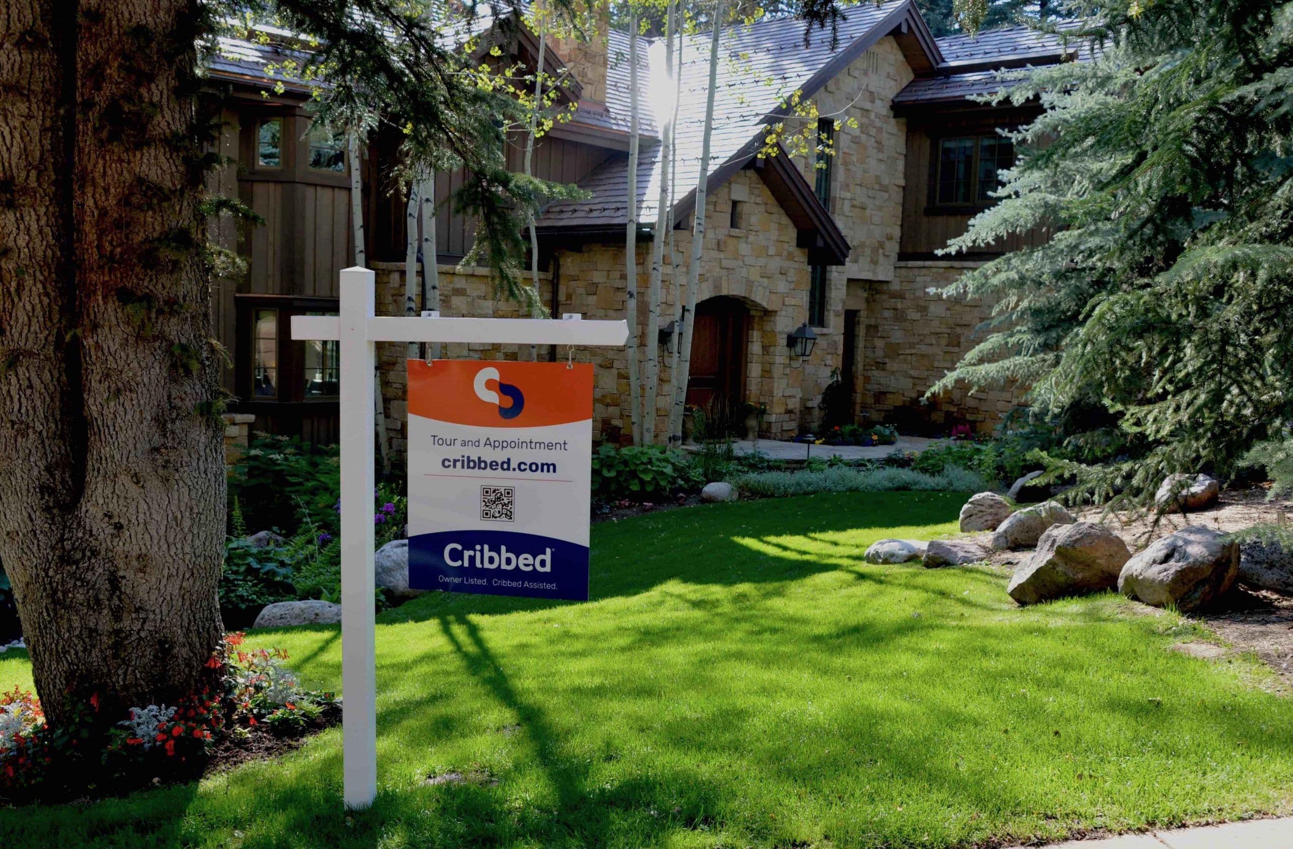 Cribbed for-sale sign in front of a stone house